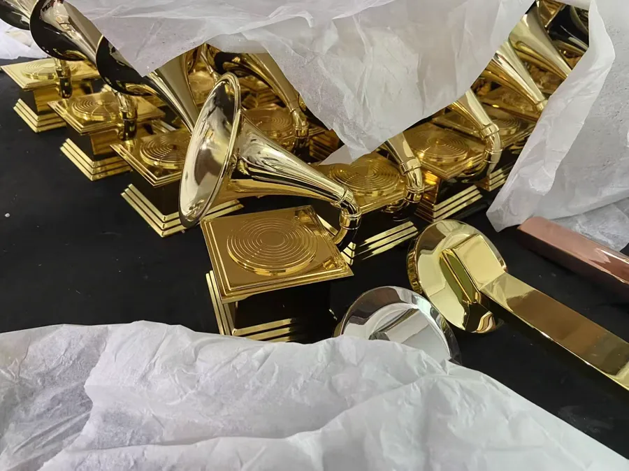 Gold-colored gramophone-shaped awards with protective packing material on a production table